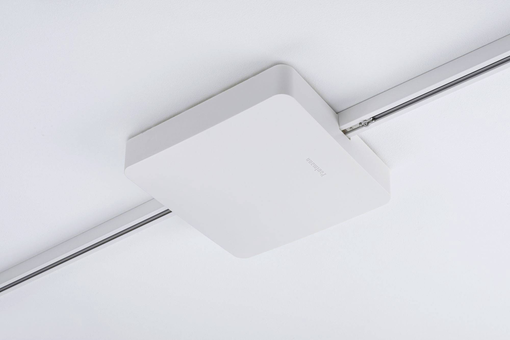 Obdĺžnikové biele stropné svetlo namontované na koľajnici zabezpečuje rovnomerné osvetlenie miestnosti.