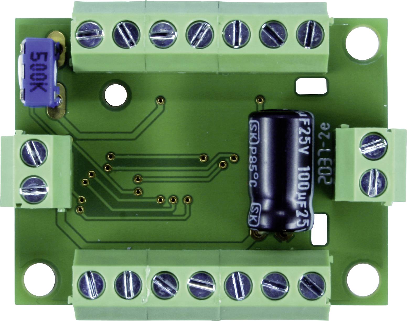 Zelená elektronická doska plošných spojov s viacerými skrutkovými svorkami, modrým potenciometrom a čiernym kondenzátorom, pohľad zhora.