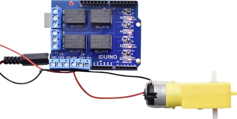 Elektronický obvod s modrou doskou a žltým motorom, prepojený červenými a čiernymi káblami. Označenia: RELAY1 až RELAY4.