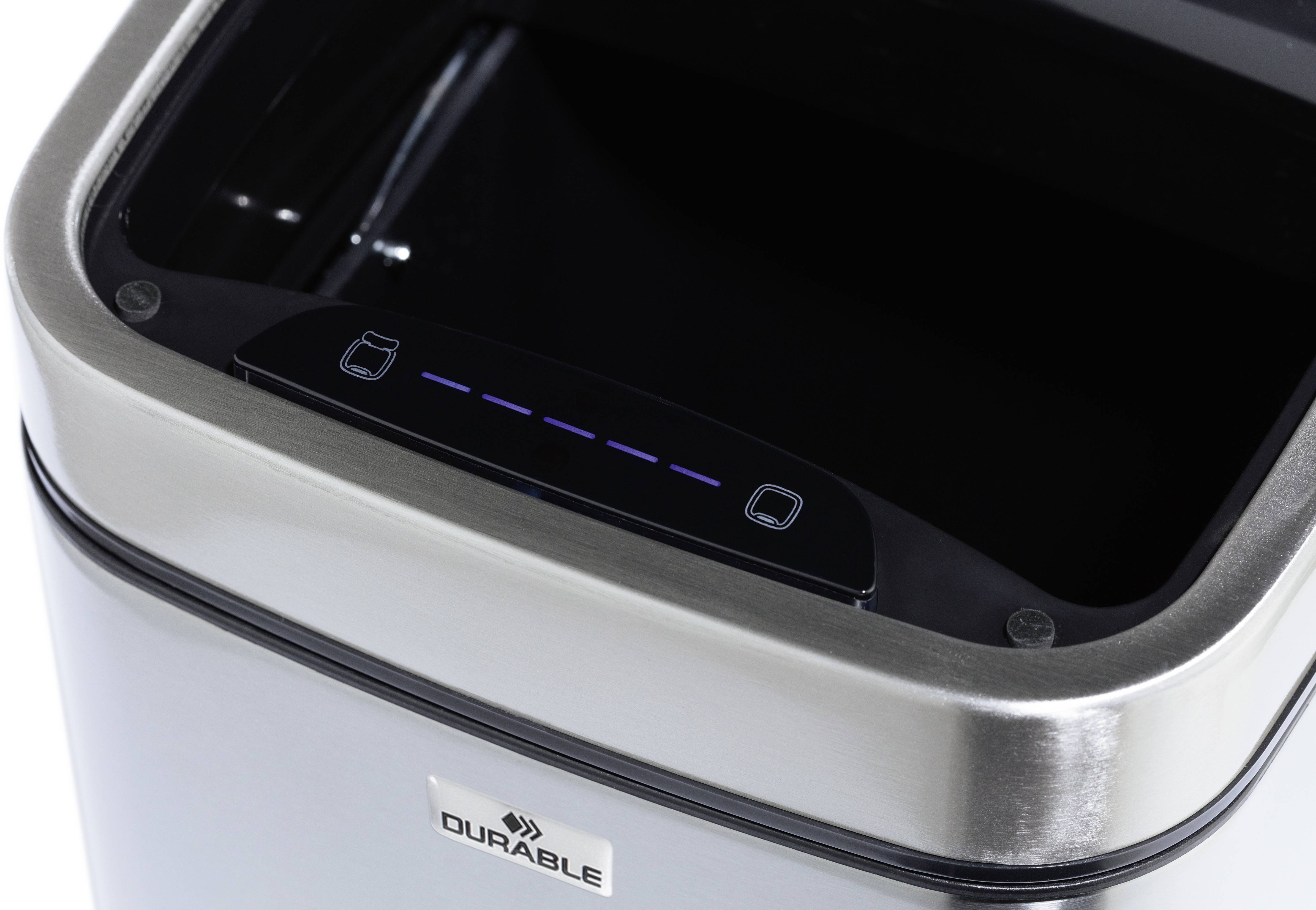 Strieborný odpadkový kôš so čiernym elektronickým vekom, ktorý sa zdá byť ovládaný senzorom. Značka 'Durable'.