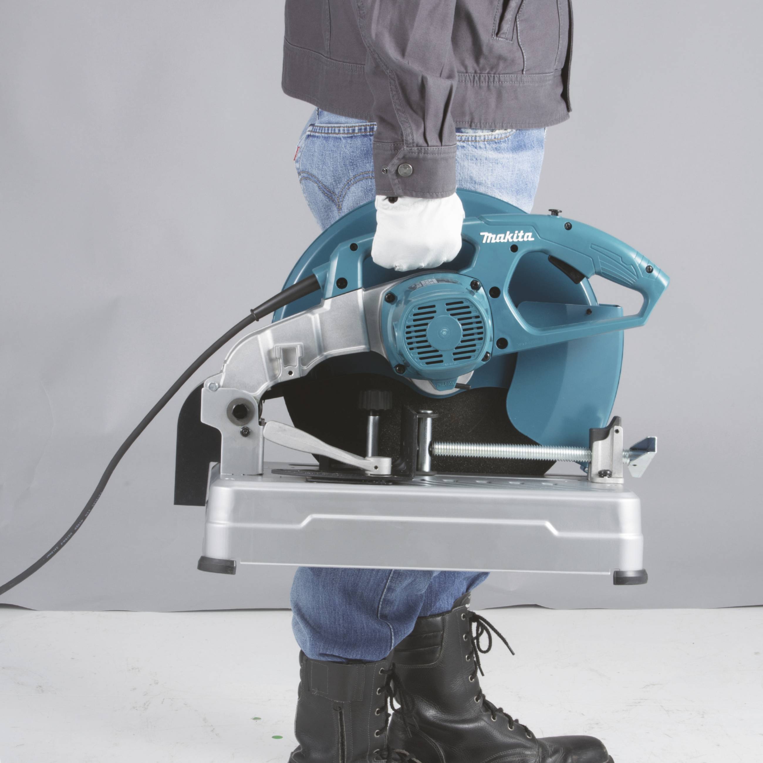 Osoba drží prenosnú modrú elektrickú pílu značky Makita, pripravenú na použitie.