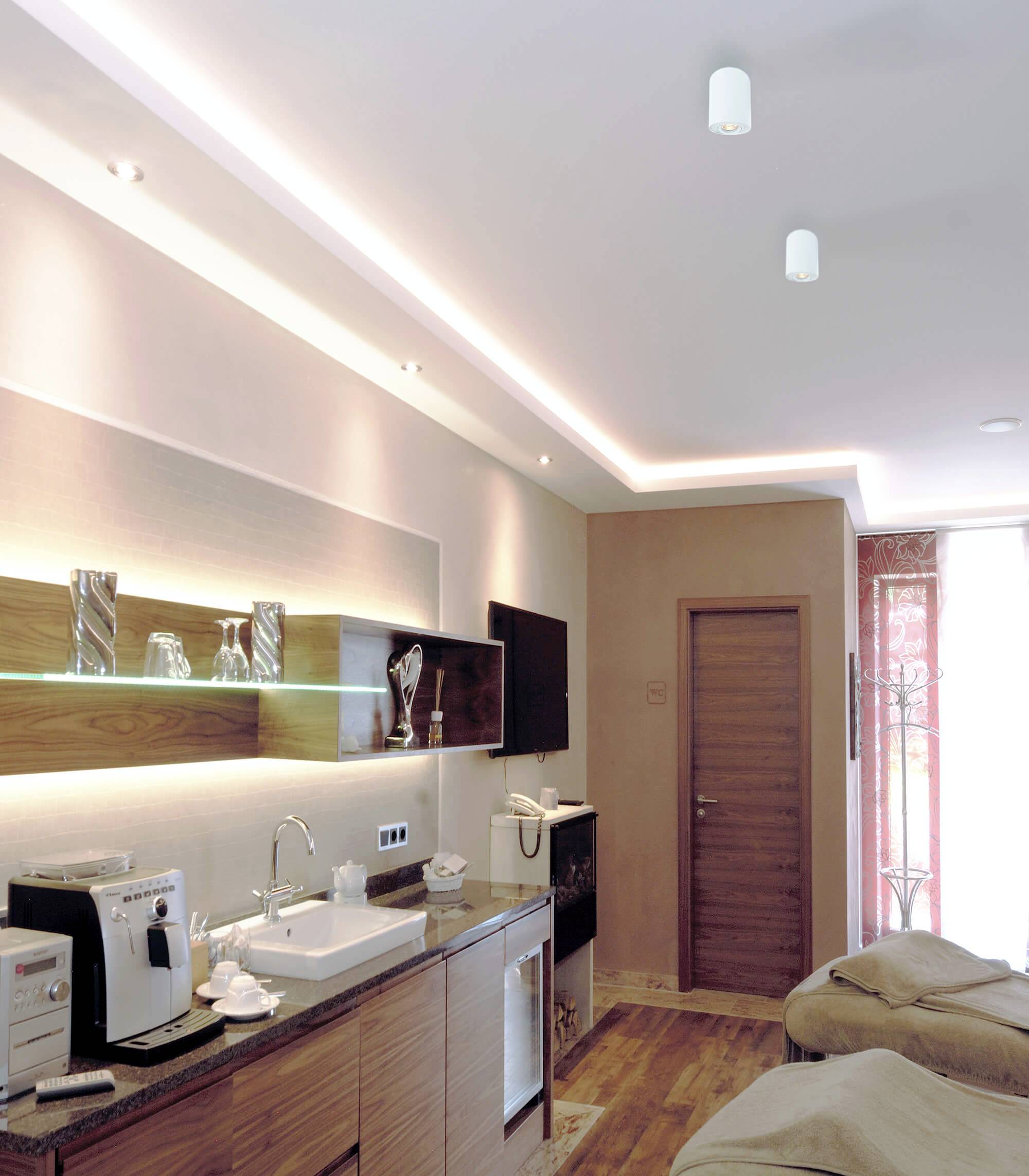 Ošetrovňa s masážnymi stolmi, moderným dizajnom, drevenou podlahou, osvetlením a umývacou zónou. Uvoľnená, svetlá atmosféra.