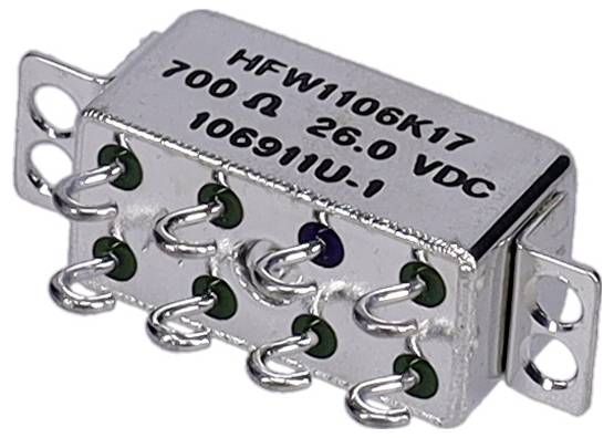 Strieborný elektronický komponent so sériovým číslom 'HFW1106K17' a špecifikáciami '700 Ω 26,0 VDC', s viacerými kovovými kolíkmi.