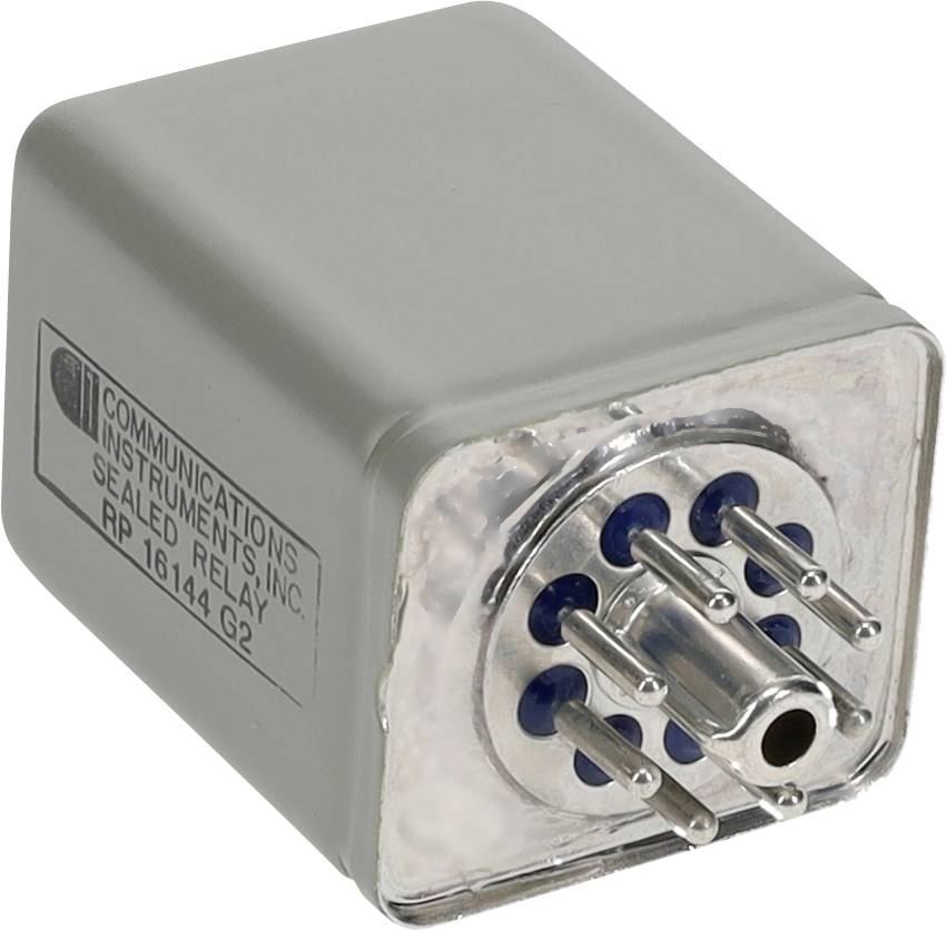 Obdĺžnikový kovový elektronický komponent s viacerými kolíkmi na jednej strane, označený "Communications Instruments Inc. Sealed Relay RP16144G2".