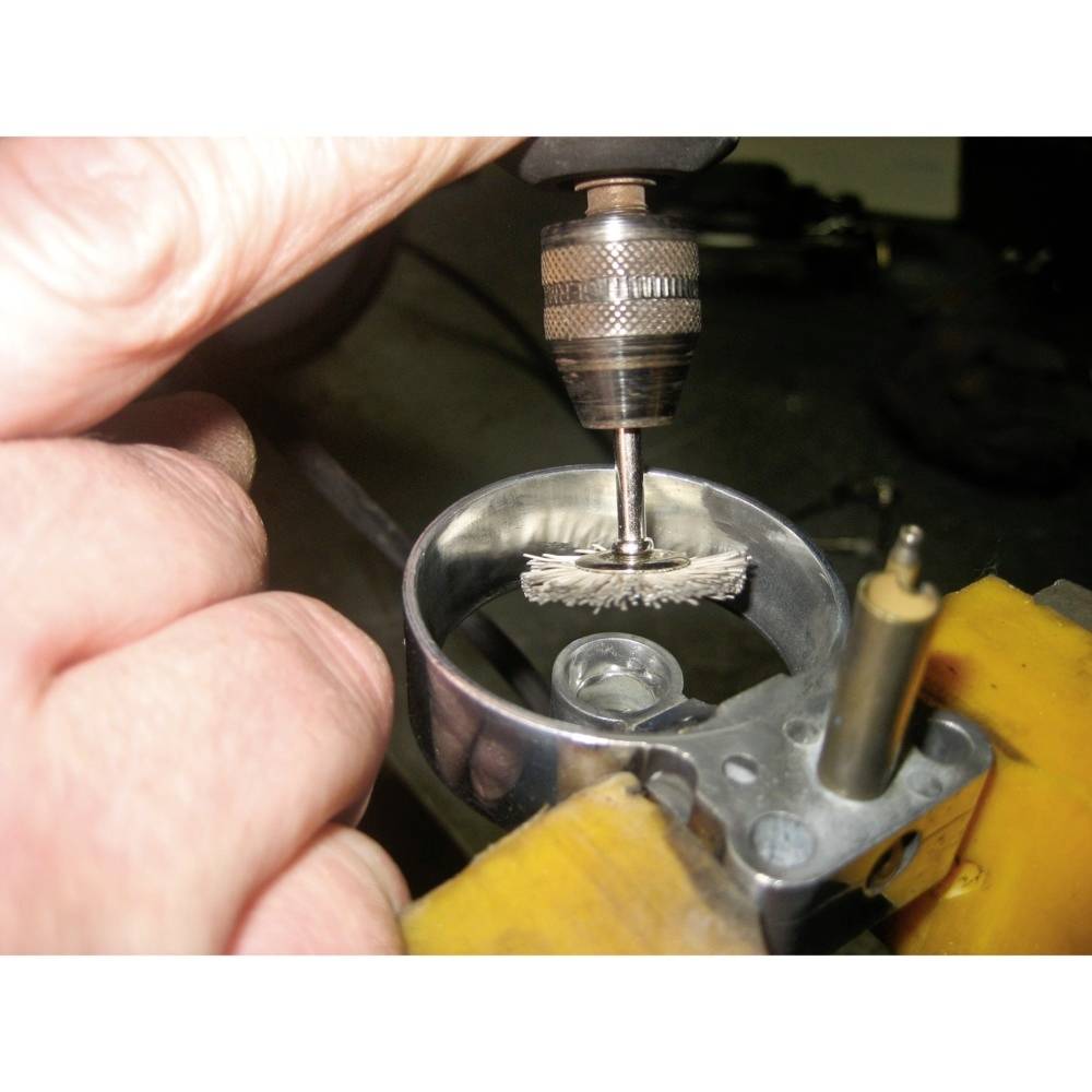 Ruka vedie rotujúci nástroj na leštenie alebo opracovanie kovového predmetu.