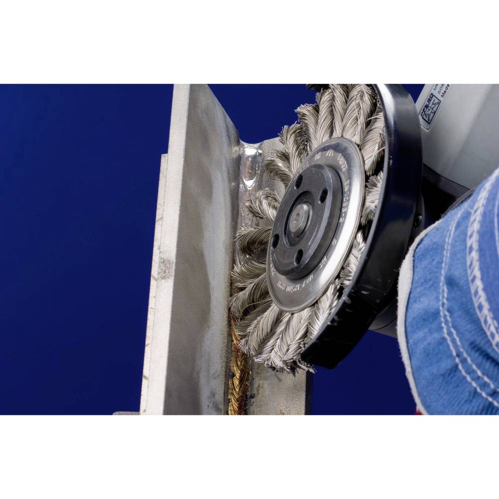 Drôtená kefa čistí hranu kovovej dosky. Rotujúce štetiny odstraňujú nečistoty a hrdzu z povrchu.