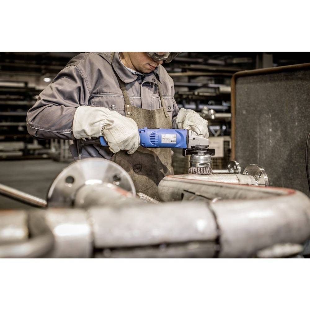 Osoba v ochranných okuliaroch a rukaviciach používa elektrickú brúsku na kovovej trubke v dielni.