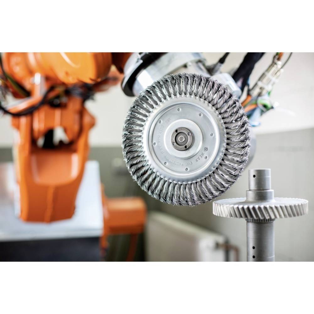 Priemyselný robot s kovovitou kefou presne opracováva ozubené koleso. V pozadí je rozmazaná robotická paža.