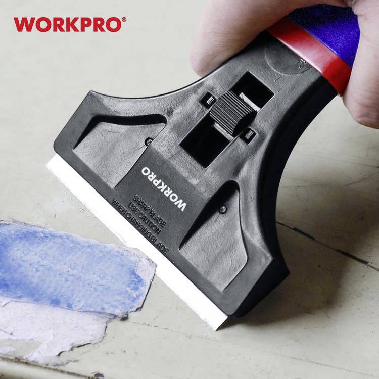 Ruka drží nástroj s čepeľou a odstraňuje modrú farbu z povrchu. Hore vľavo je červené logo 'WORKPRO'.