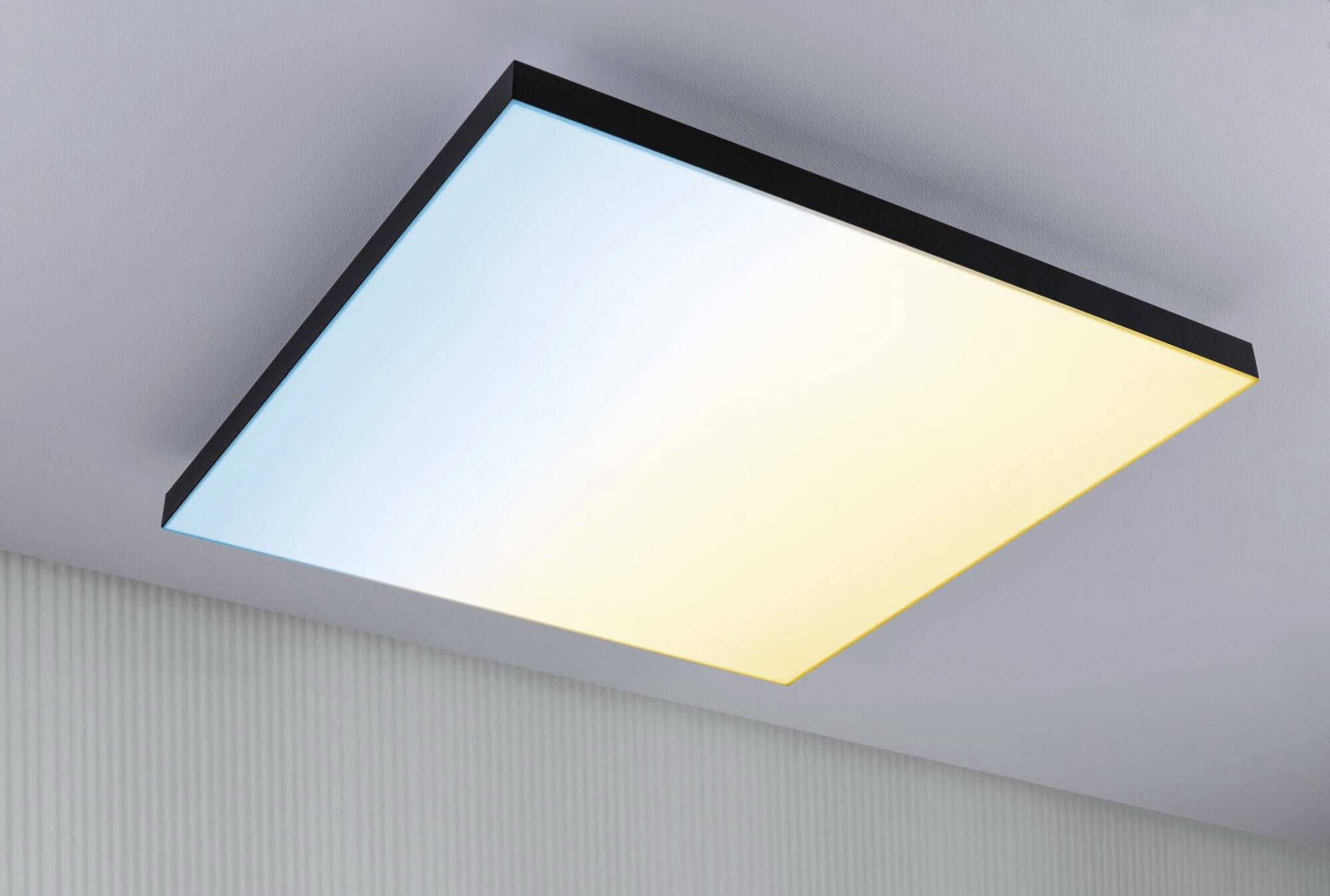 Obdĺžniková stropná lampa s farebnými prechodmi od modrej po žltú. Je namontovaná na bielom strope a pôsobí moderne a elegantne.