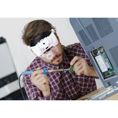 Osoba spájkuje elektronickú dosku spájkovacou pákou a pritom má nasadené zväčšovacie okuliare.