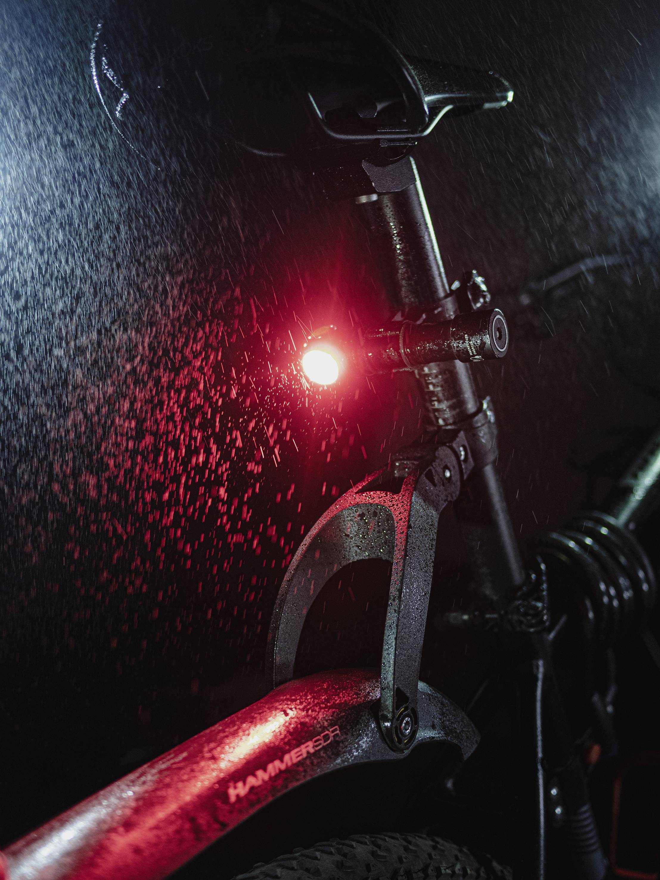 Bicykel v daždi, detailný záber: Jasne červené zadné svetlo zdôrazňuje bezpečnosť počas nočných jázd.