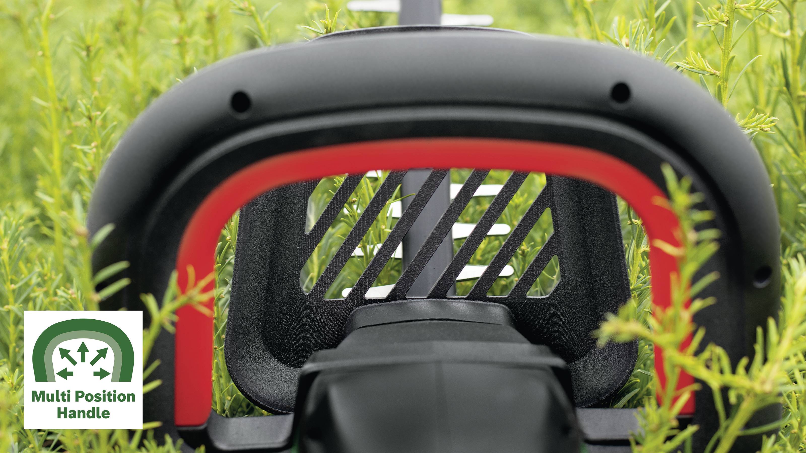 Detailný záber krovinorezu v záhrade s tabuľkou, ktorá zobrazuje nápis "Multi Position Handle".