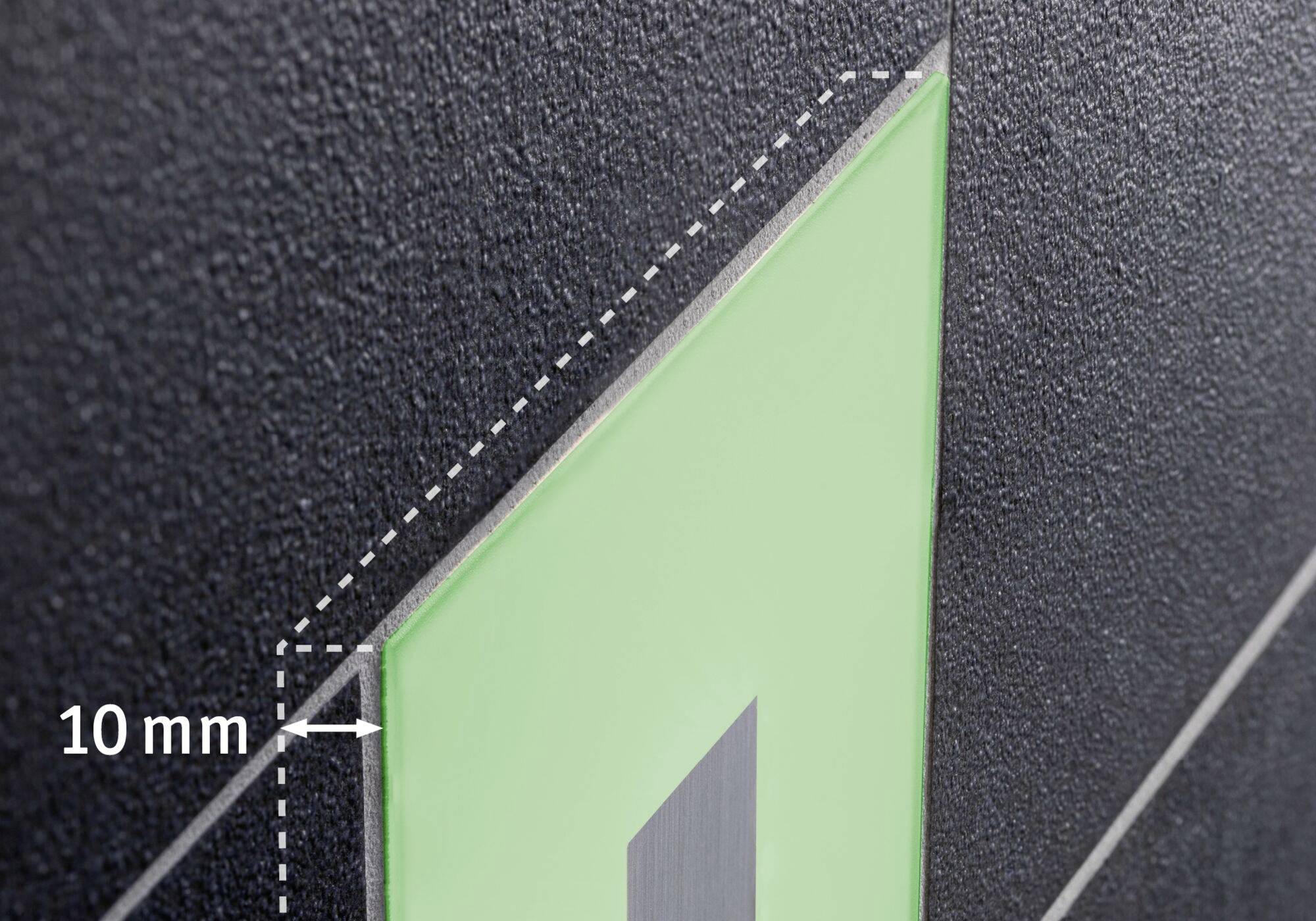 Detailný záber zelenej dlaždice na tmavom povrchu so vzdialenosťou 10 mm. Prerušovaná čiara znázorňuje vzdialenosť.