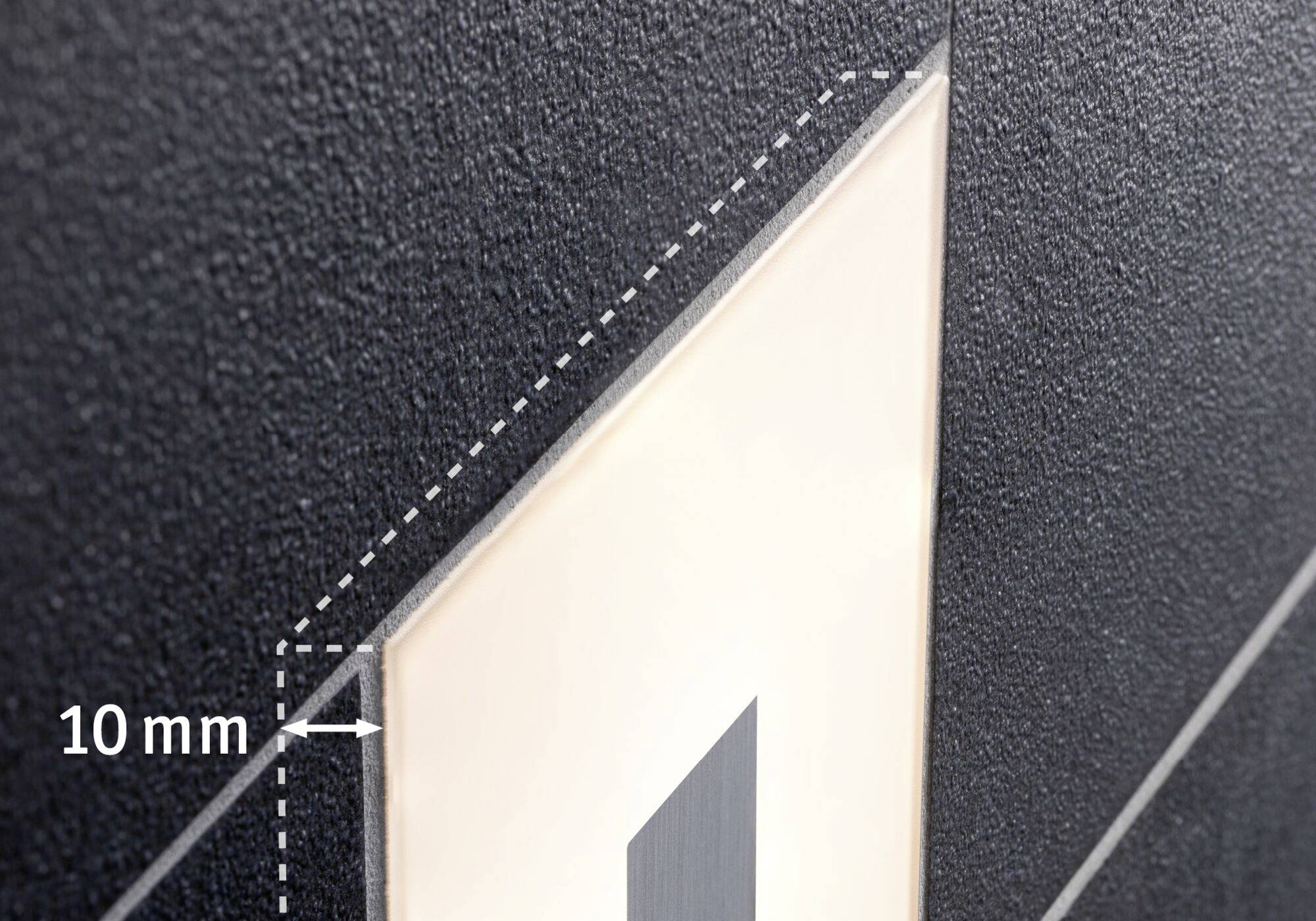 Detail zblízka čierneho štruktúrovaného povrchu s 10 mm výstupkom smerujúcim na zvýraznenú dosku.