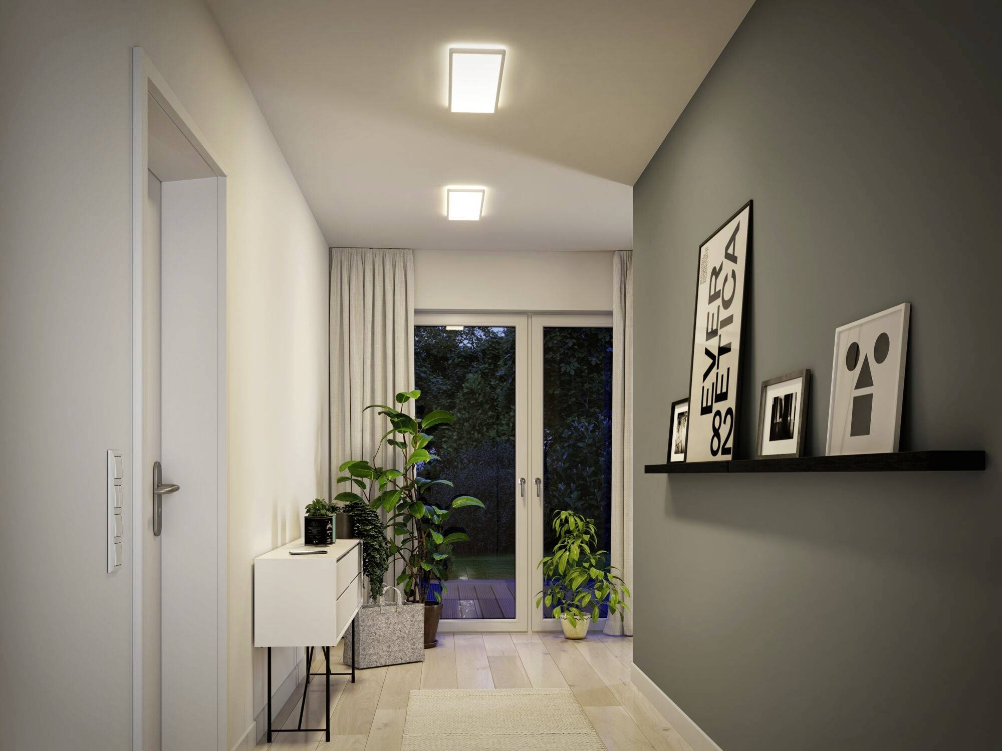 Moderne priestranné zádverie s bielou skriňou, zelenými rastlinami a políčkou s obrázkami, ktoré vedie k preskleným dverám.