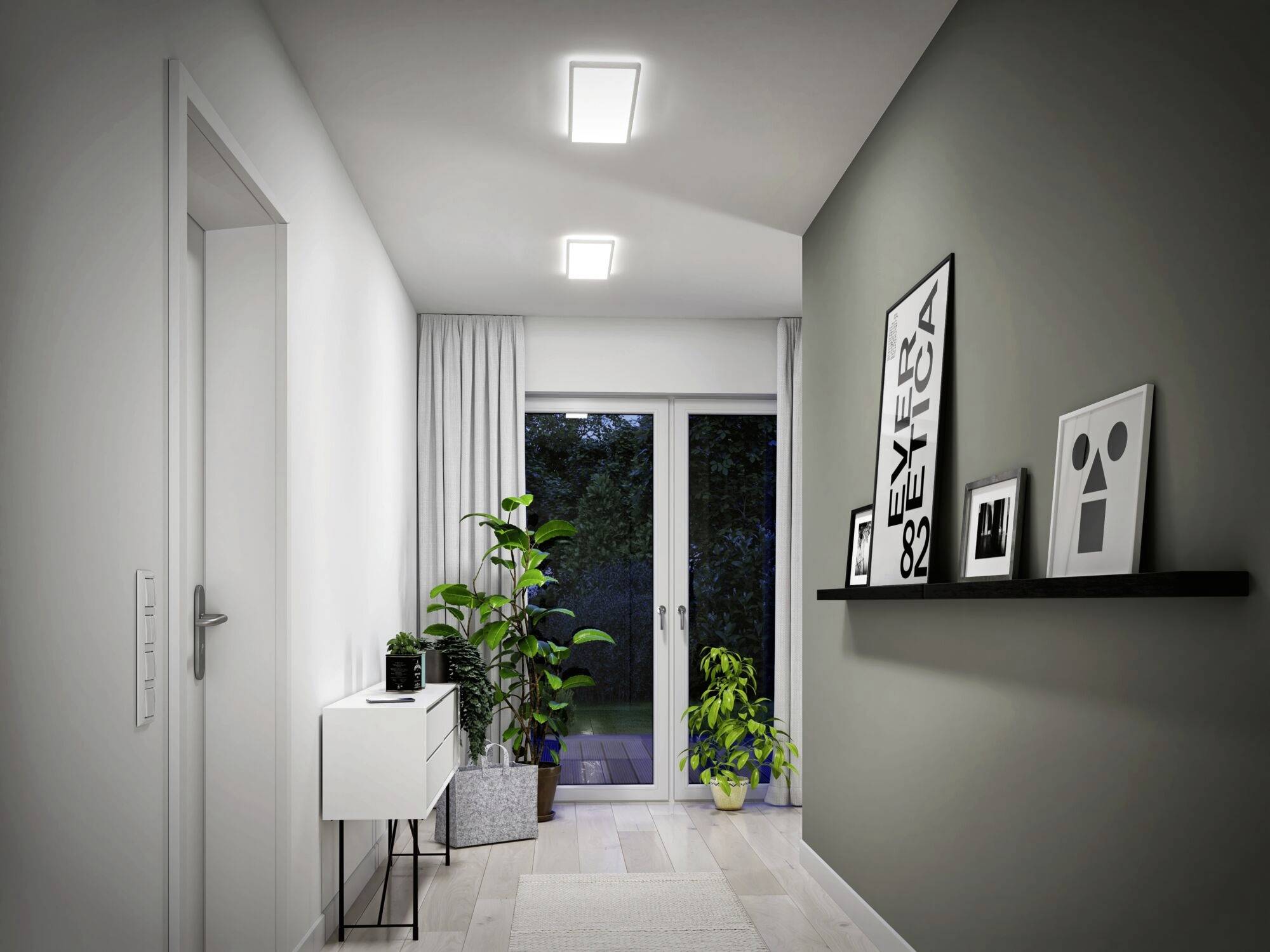 Moderná chodba s bielymi stenami, rastlinami, malým stolíkom a políčkami s fotografiami a umeleckými dielami. Sklenené dvere vedú von.