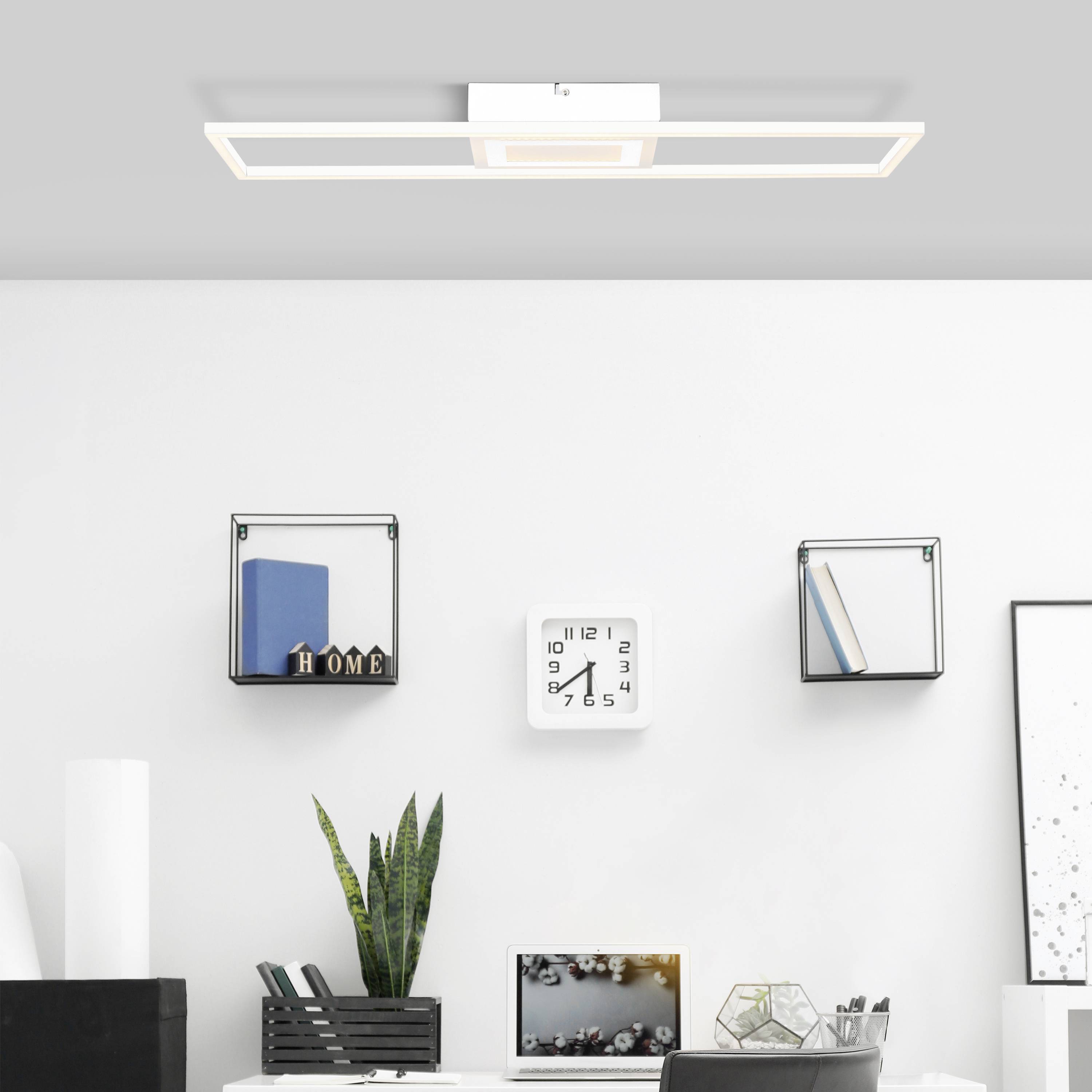 Moderná obývačka so štvorcovou stropnou lampou, stenovou policou s dekoráciami a stolom s rastlinami a knihami.