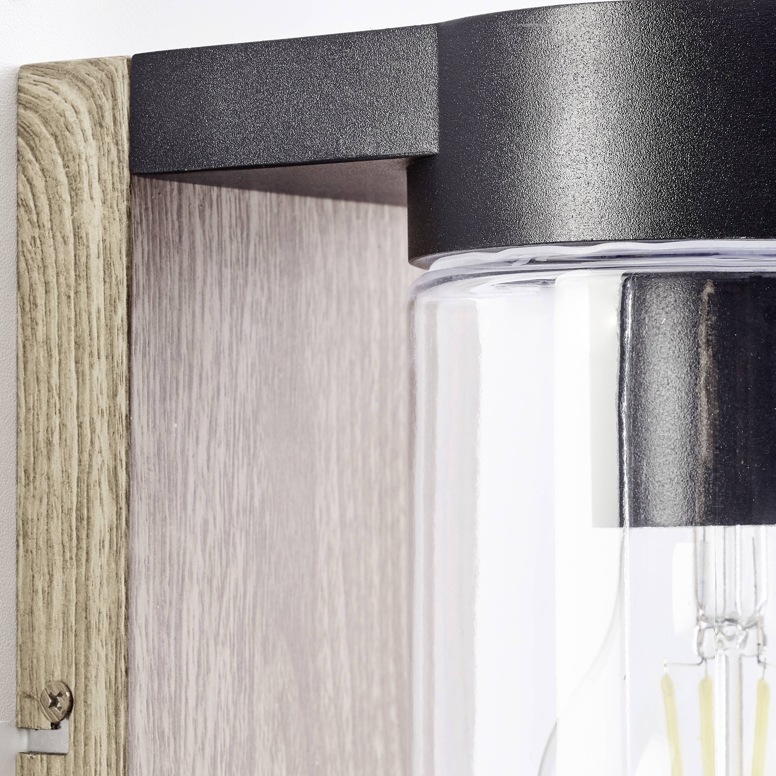 Detailný záber modernej nástennej lampy s prvkami z dreva a kovu. Žiarovka je viditeľná za priehľadným sklom.