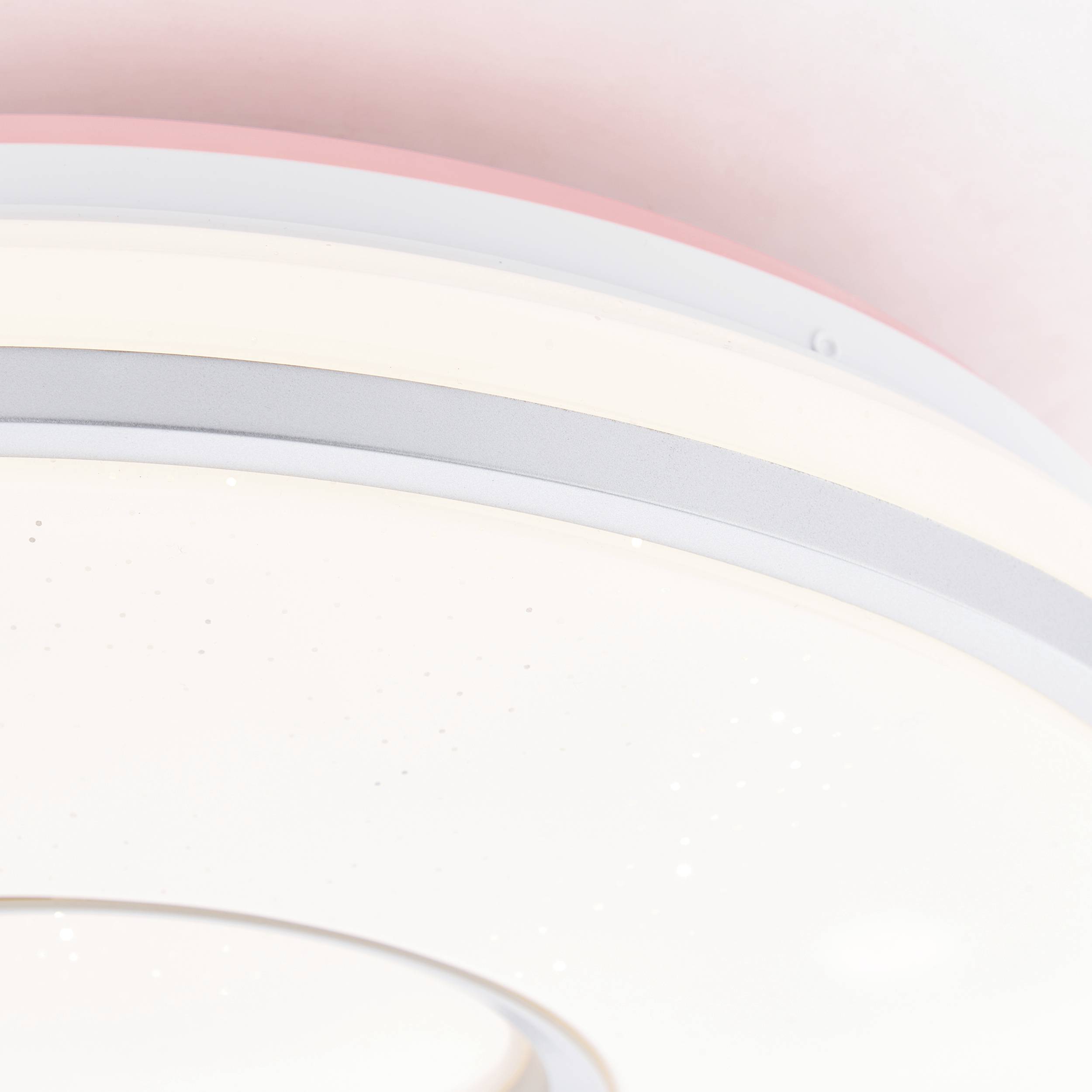 Moderný, okrúhly stropný ventilátor so vstavaným osvetlením a hladkým bielym povrchom na pastelovo sfarbenom pozadí.