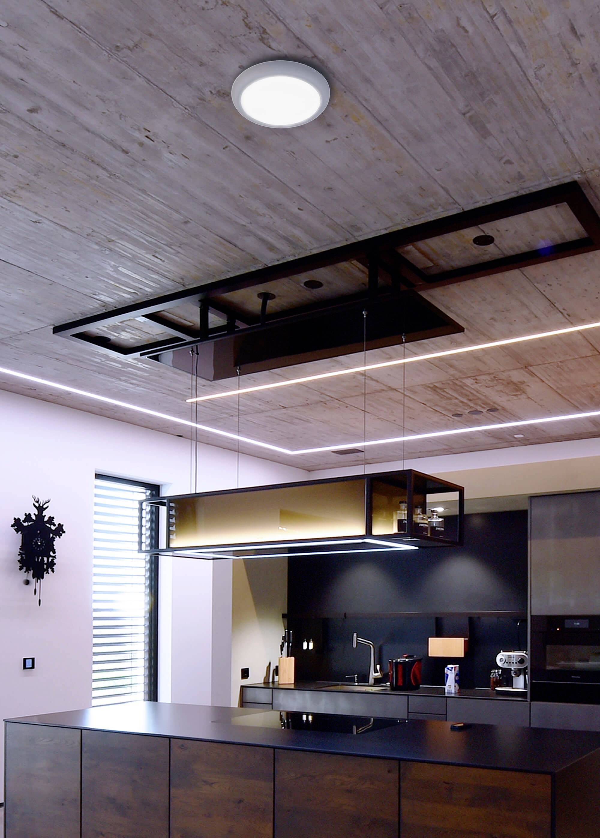 Moderná kuchyňa so zavesením stropným regálom nad ostrovčekom, pod ktorým sú tmavé drevené nábytky. Elegantné osvetlenie zvýrazňuje dizajn.