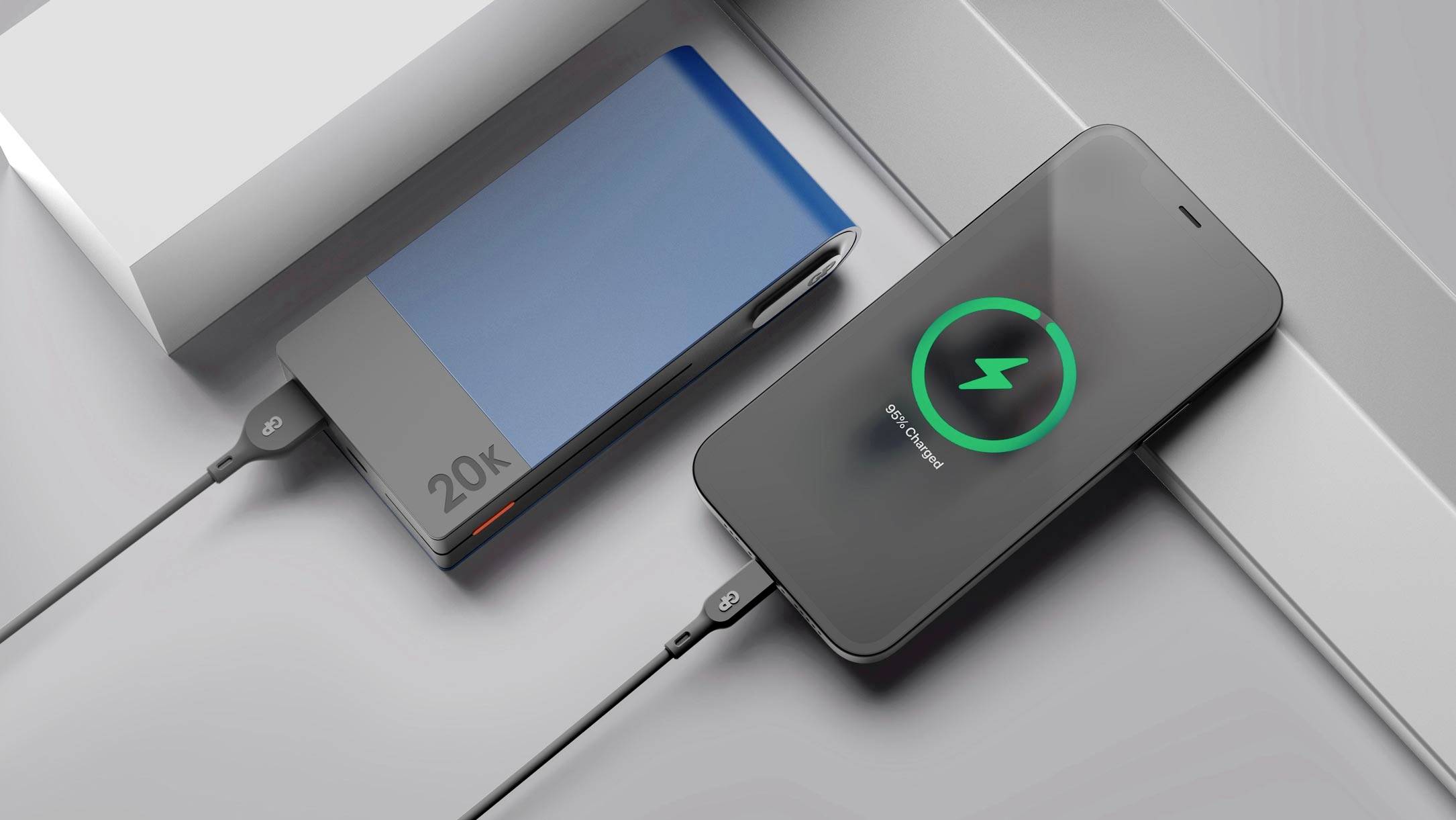 Smartfón sa bezdrôtovo nabíja z powerbanky. Powerbank má dizajn v modro-sivej farbe a kapacitu 20 000 mAh.