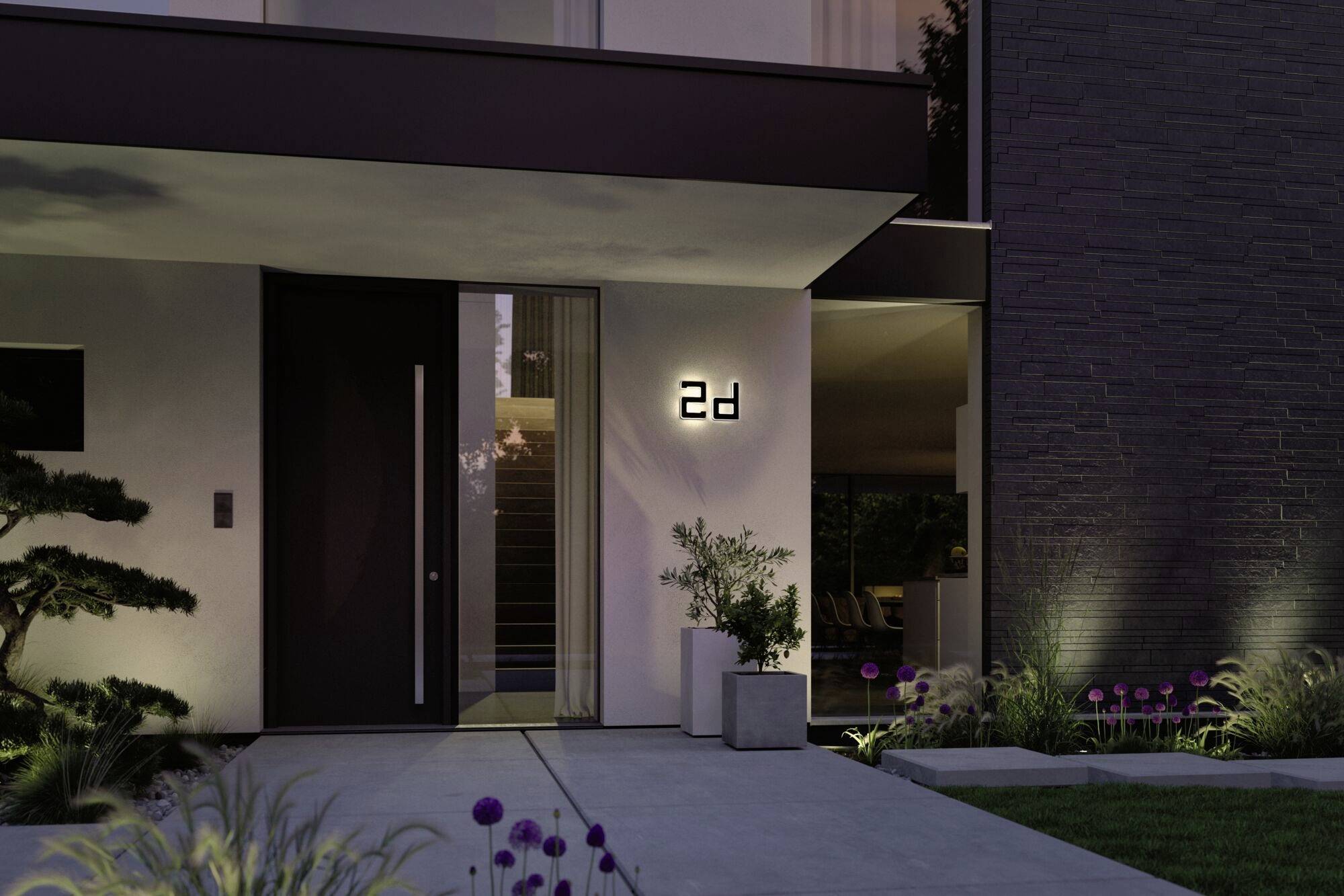 Moderný dom za súmraku s osvetleným domovým číslom '24', lemovaný starostlivo udržiavanou zeleňou a s priamym vstupom ku vchodovým dverám.