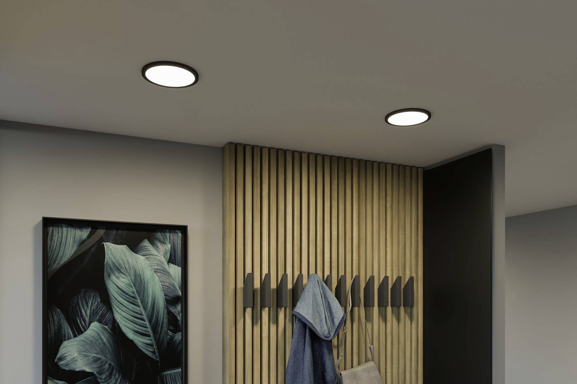 Osvetlená chodba s moderným dizajnom: drevené obloženie s háčikmi, na ktorom visí bunda. Na stene visí obraz s listovým motívom.