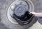 Osoba drží čiernu zachytávaciu nádobu pod kolesom veľkého vozidla, aby zachytila olej vytekajúci z ventilu.