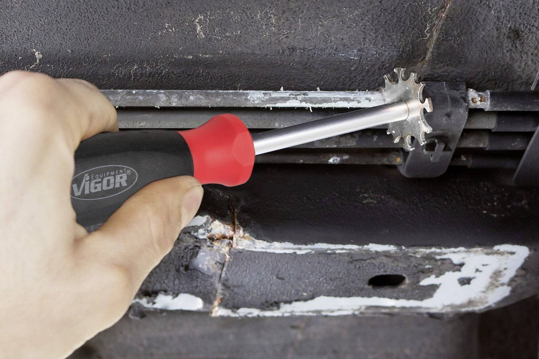 Ruka používa červený skrutkovač na uvoľnenie svorky z kovovej plochy.