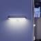 Moderná nástenná lampa na bielej stene osvetľuje chodbu v minimalistickom interiéri.
