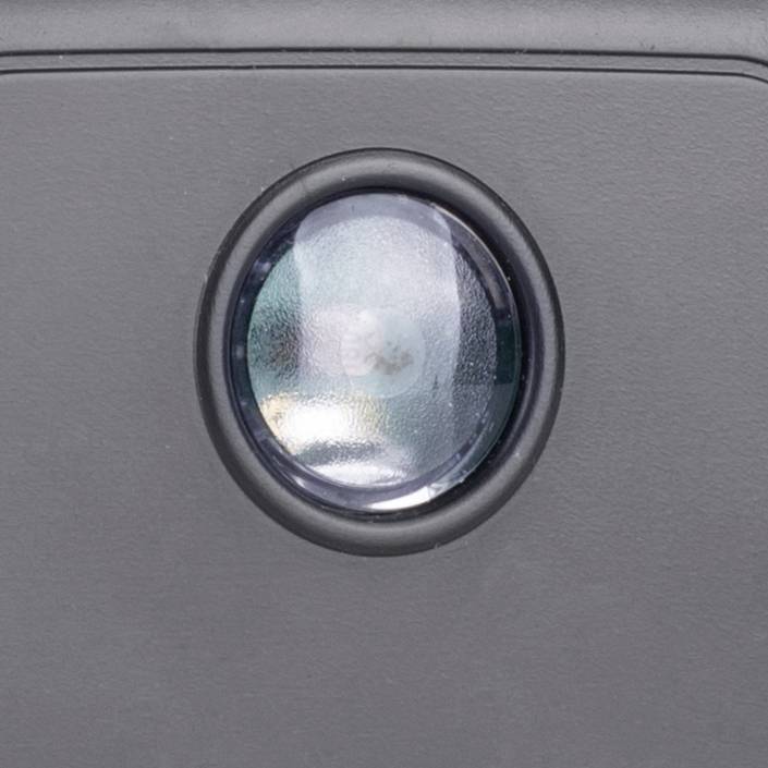 Čierny objektív fotoaparátu na sivom zariadení, bez ďalšieho kontextu alebo funkcie.