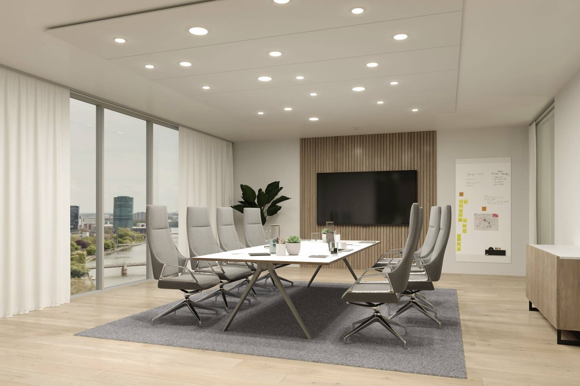 Moderná rokovacia miestnosť s veľkým stolom, obklopená ôsmimi sivými stoličkami. Na stene veľký monitor a tabuľa. Okná s výhľadom na mesto.