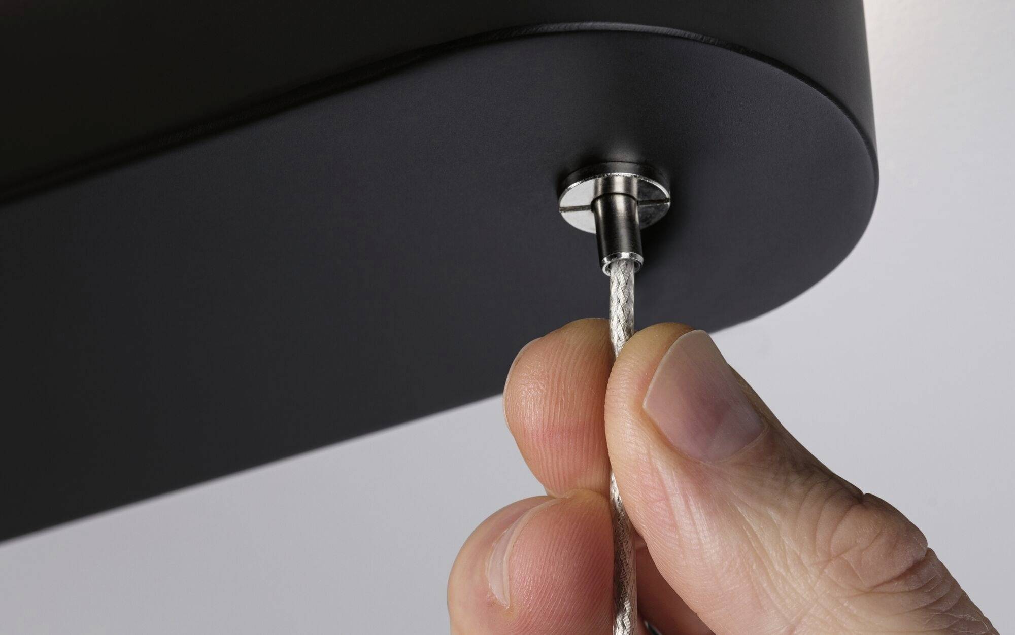 Rukaťahá za prepletený kábel, ktorý je ukotvený v kovovom kryte.