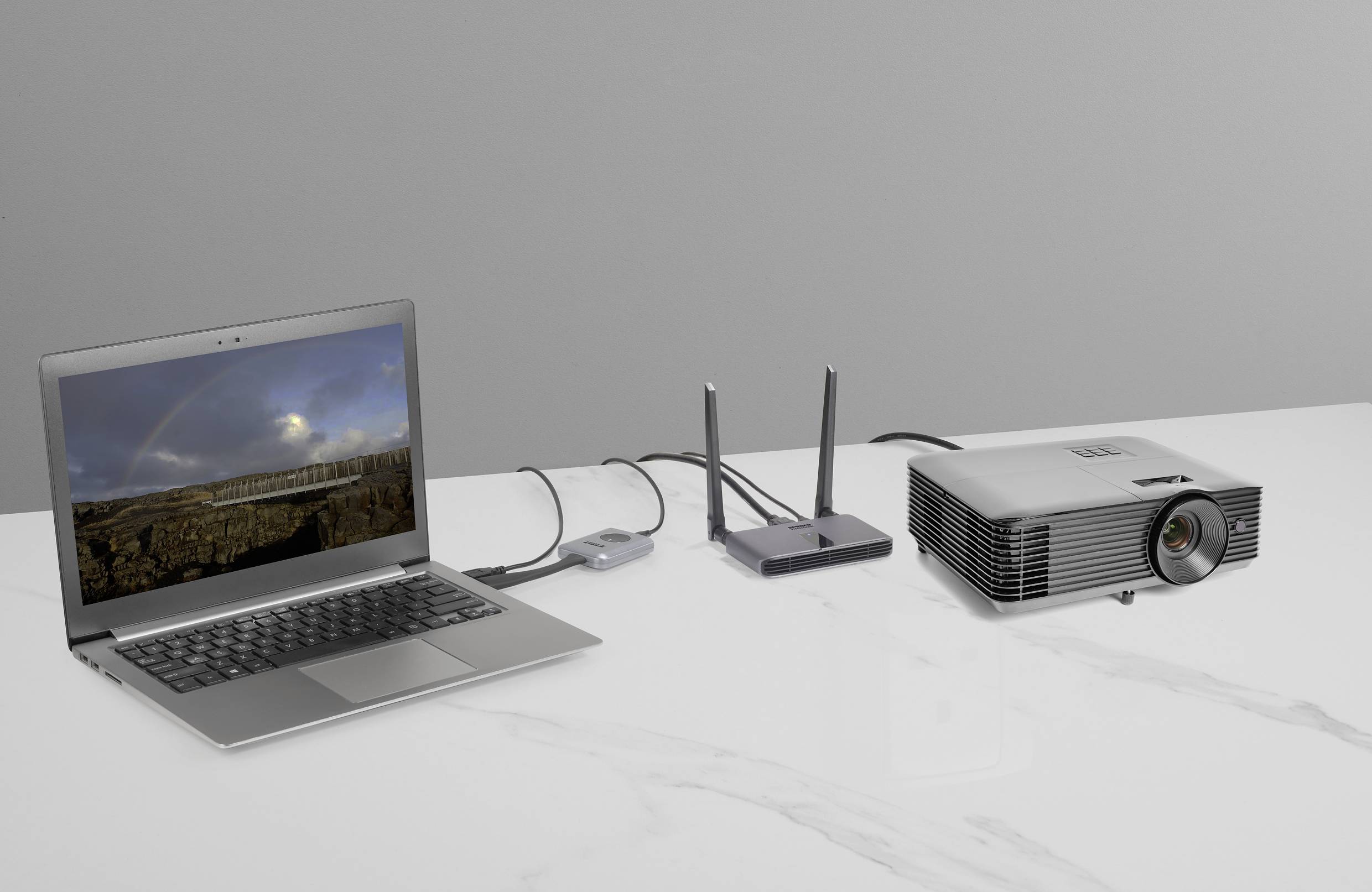 Notebook, router a projektor prepojené káblami na stole, projektor nezobrazuje žiadny obsah.