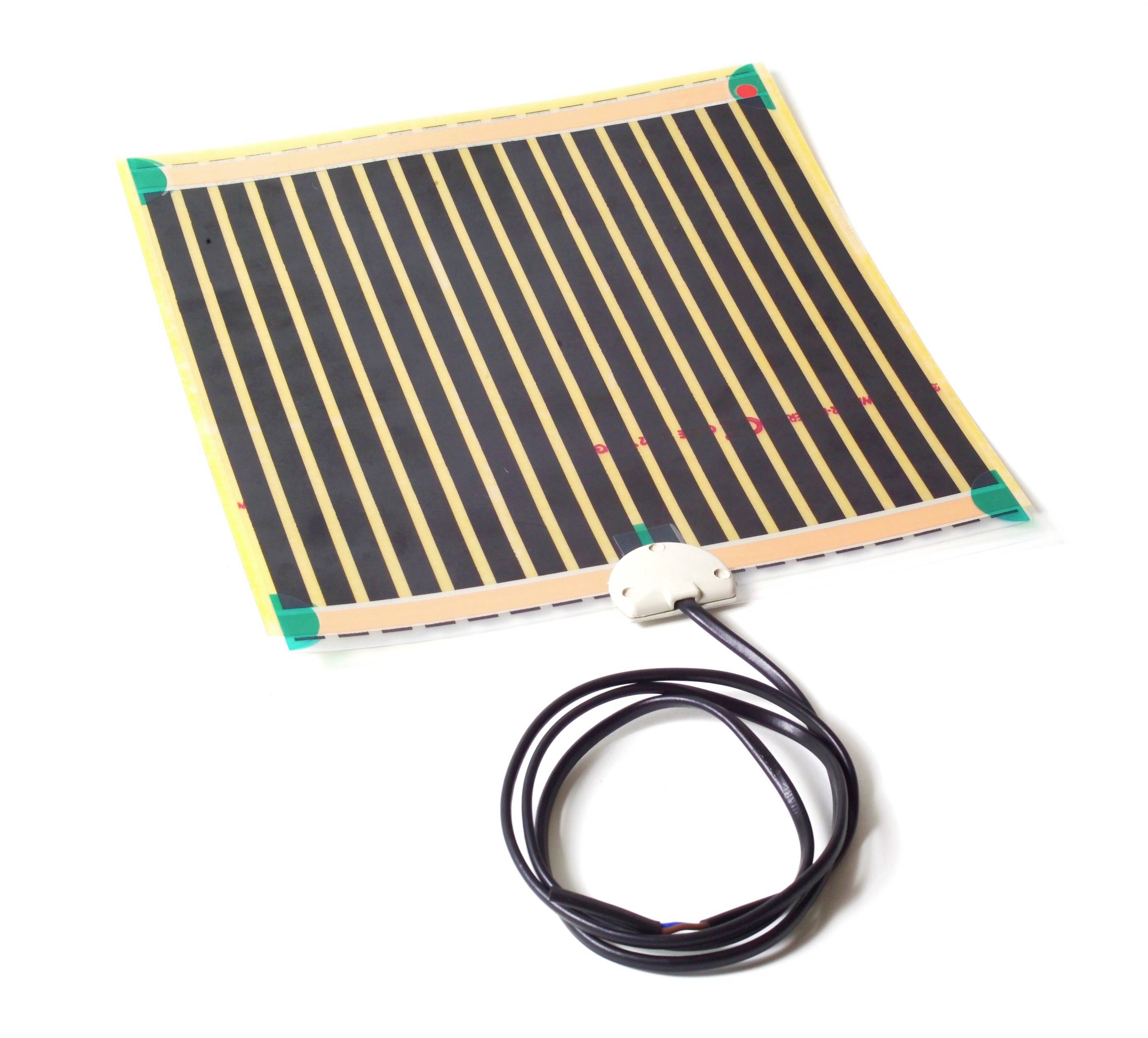 Obdĺžnikový vykurovací prvok s čiernymi a žltými pruhmi, prepojený čiernym káblom, leží na bielom pozadí.