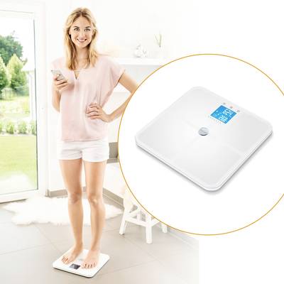 Žena sa váži na digitálnej váhe, ktorá ukazuje jej hmotnosť v kilogramoch. Pôsobí spokojne a drží smartphone.
