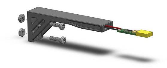 3D model zobrazuje technickú súčiastku s perami, skrutkami a elektrickými prípojkami vyčnievajúcimi z obdĺžnikového krytu.