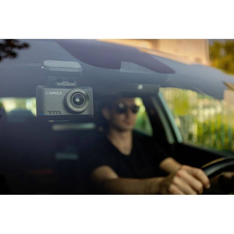 Muž šoféruje auto. Autokamera Lamax je pripevnená na vnútornej strane predného skla a zaznamenáva jazdu.