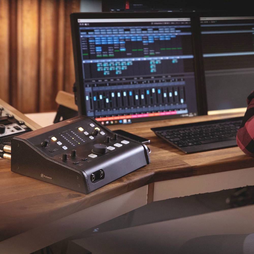 Nahrávacia štúdio s mixážnym pultom, počítačovými monitormi a klávesnicou. Audiosoftér zobrazuje zvukové stopy a ovládacie prvky.