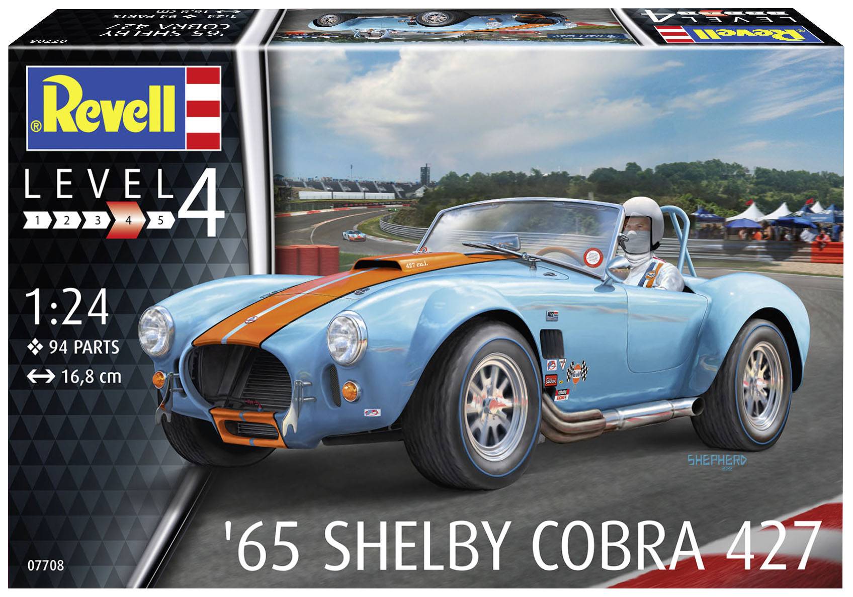 Modré Shelby Cobra 427 modelové auto od Revell v mierke 1:24 s oranžovými pruhmi, zobrazené na pretekárskej dráhe.