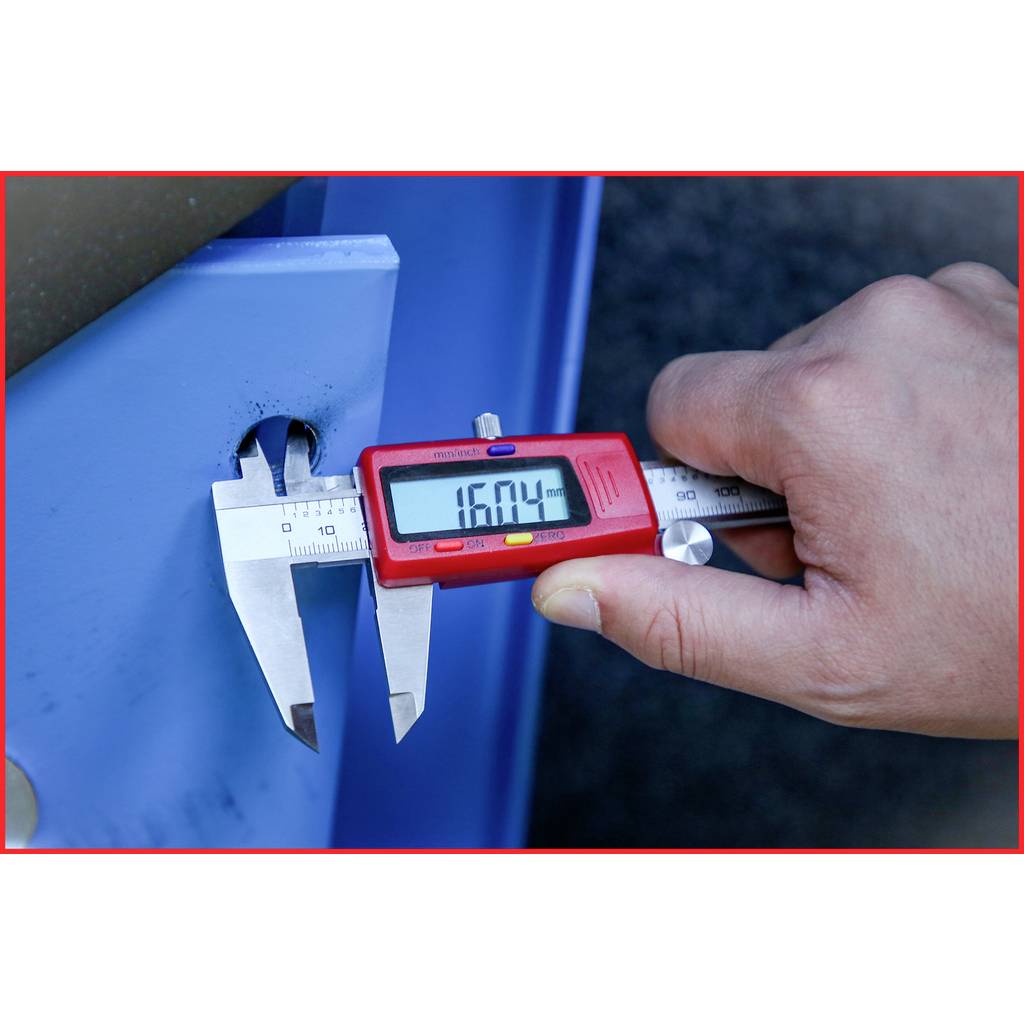 Ruka meria hĺbku modrého kovového kusu digitálnym posuvným meradlom. Na displeji je zobrazená hodnota '16,04'.