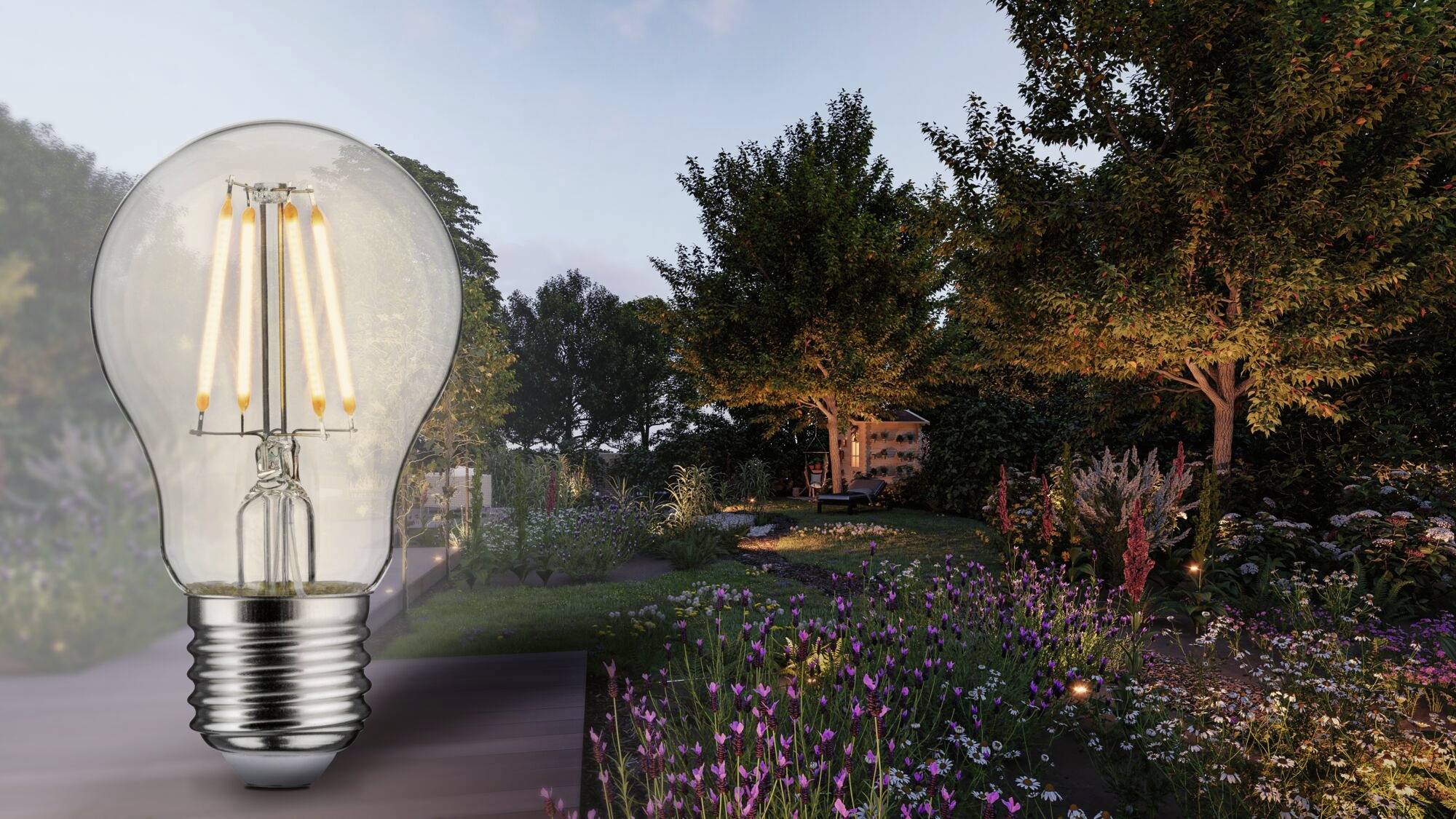 Žiarovka sa vznáša nad osvetlenou záhradou za súmraku, s kvitnúcimi kvetmi a stromami vyžarujúcimi teplé svetlo.