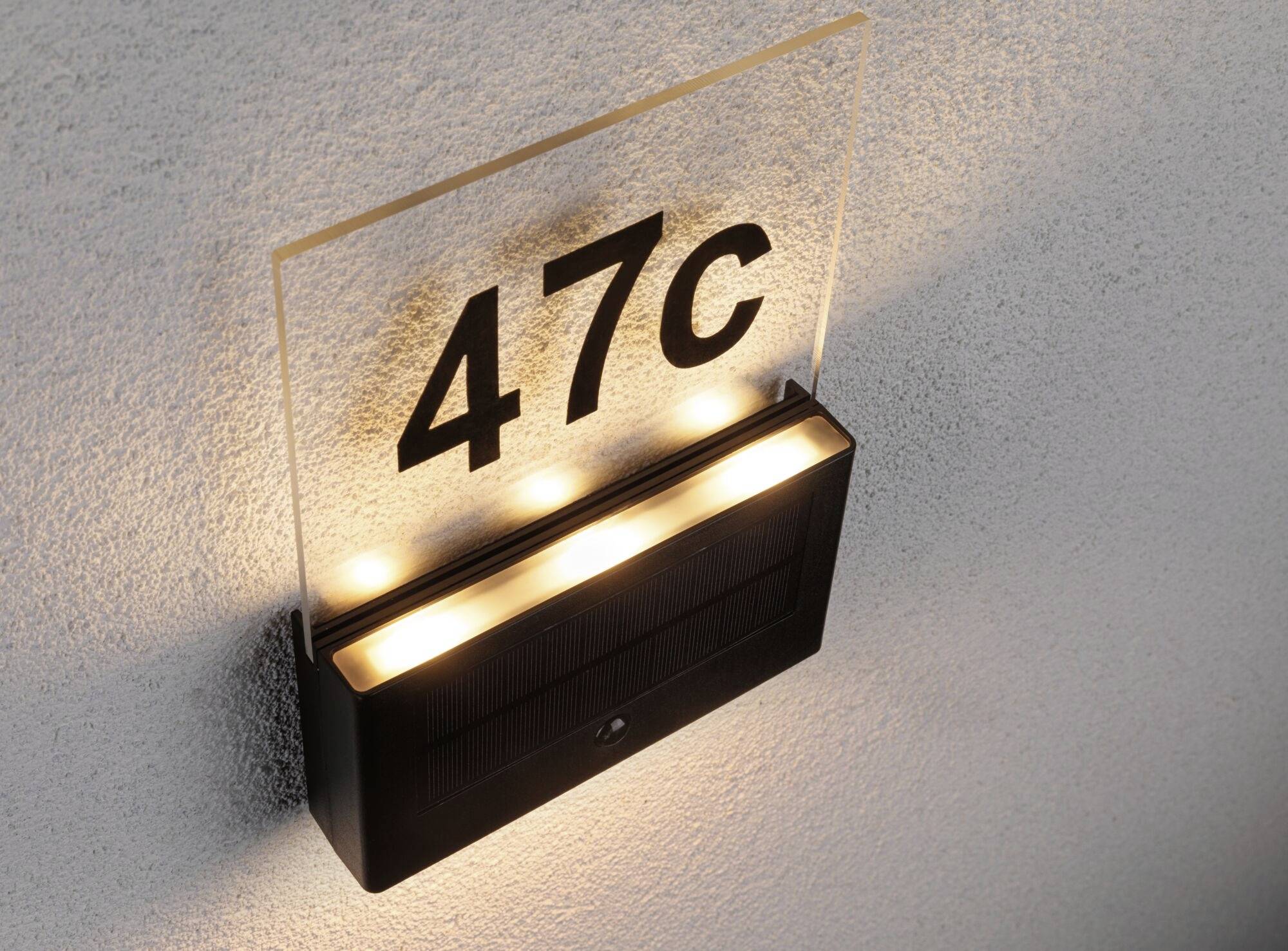 Solárne osvetlená domová tabuľa s číslom '47C', namontovaná na stene.