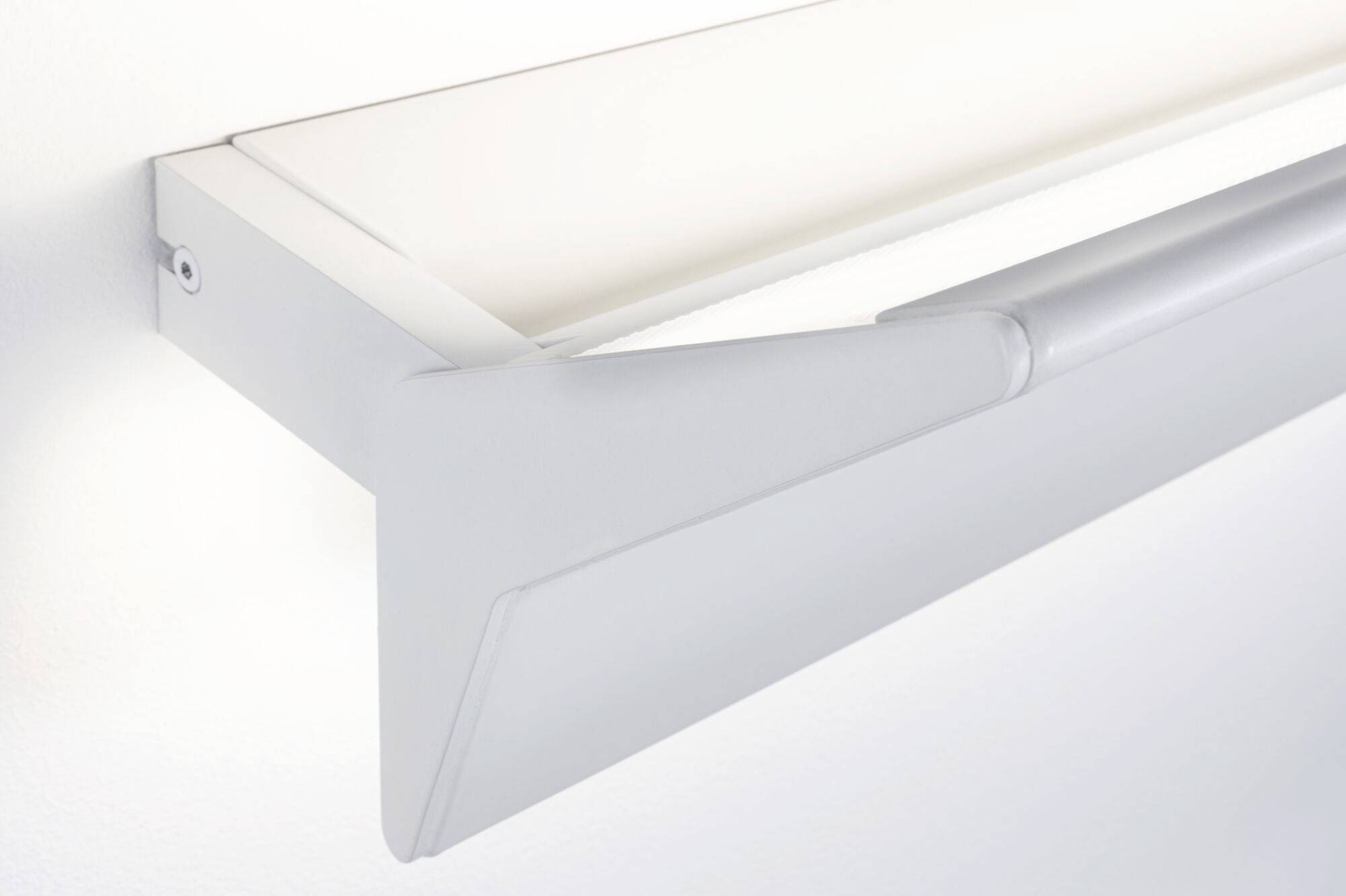 Moderná nástenná lampa s elegantným, obdĺžnikovým dizajnom namontovaná na bielej stene, vyžarujúca tlmené svetlo.