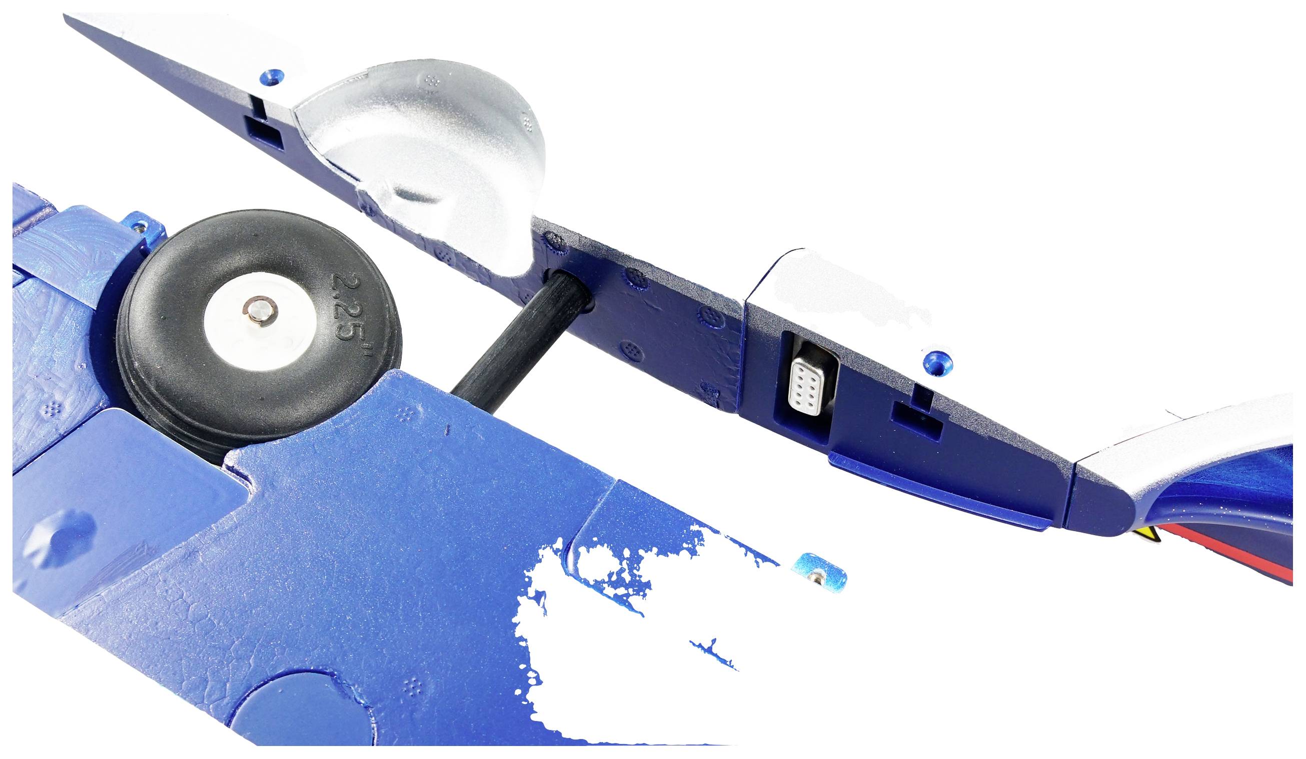 Detailný záber krídla modelárskeho lietadla v modrej farbe, kde sú zreteľne viditeľné mechanické prvky vrátane kolesa a elektronických pripojení.