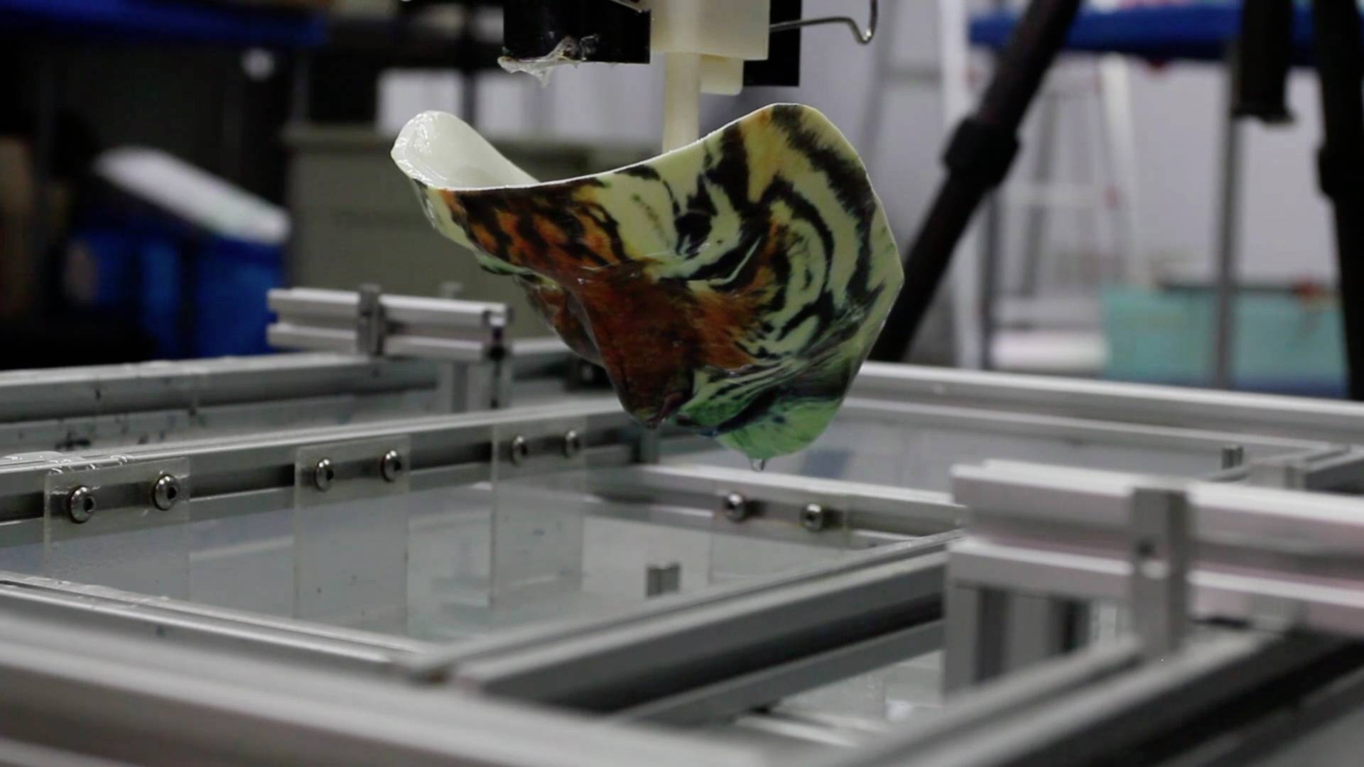 Stroj ponorí fóliu s dizajnom tigra do vody, aby potlačil objekt. Umožňuje presný tlač.