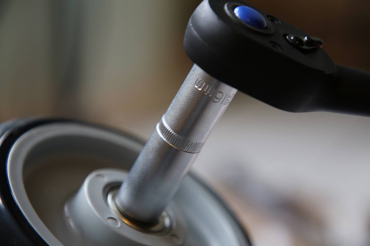 Momentový kľúč dotiahne skrutku. Detail zblízka ukazuje nástroj počas práce, zdôrazňuje presnosť a mechaniku.