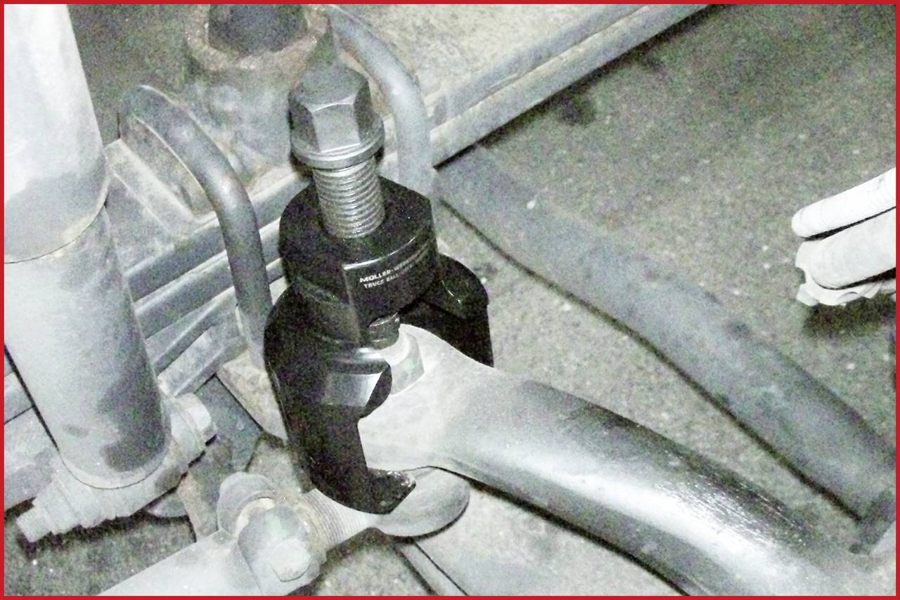 Detailný záber nástroja na opravu motorových vozidiel, ktorý odpája rameno zavesenia kolesa.