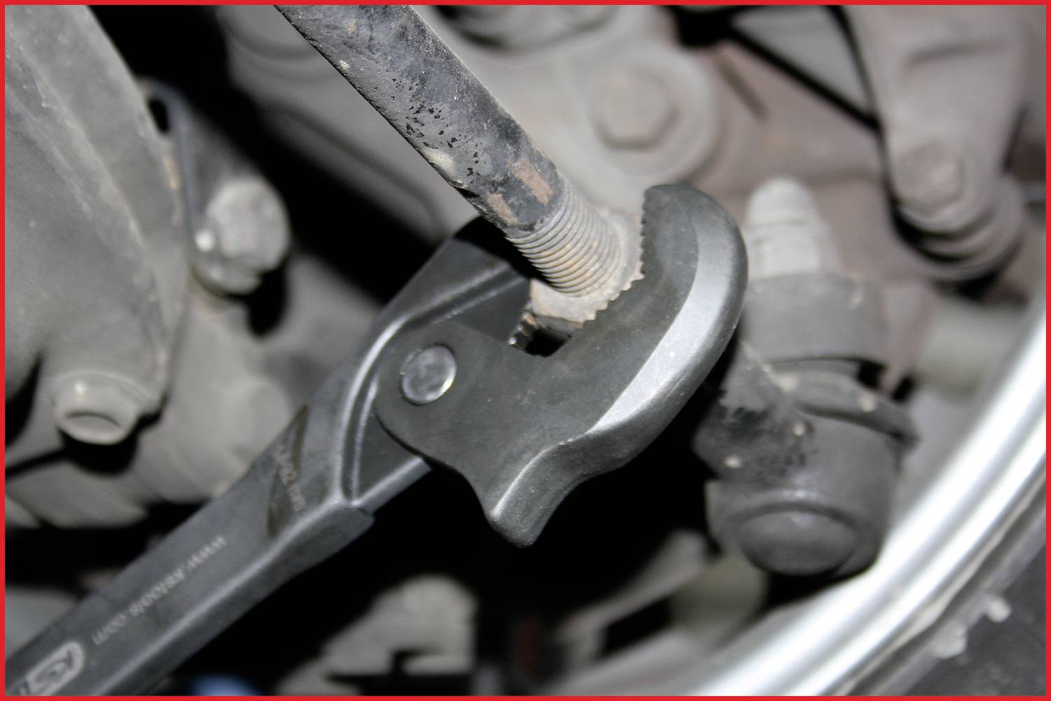 Kľúč otáča skrutku na automobile. Dôraz je kladený na interakciu medzi náradím a skrutkou, aby sa ilustrovala údržba vozidla.